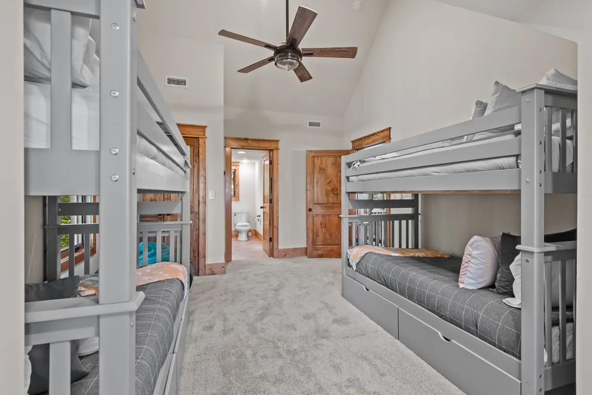 A playful bunk room with built-in bunk beds, cheerful decor, and a cozy, carpeted floor. The space is clearly designed for children, offering a safe and fun retreat for sleepovers, reading, or playing games together.
