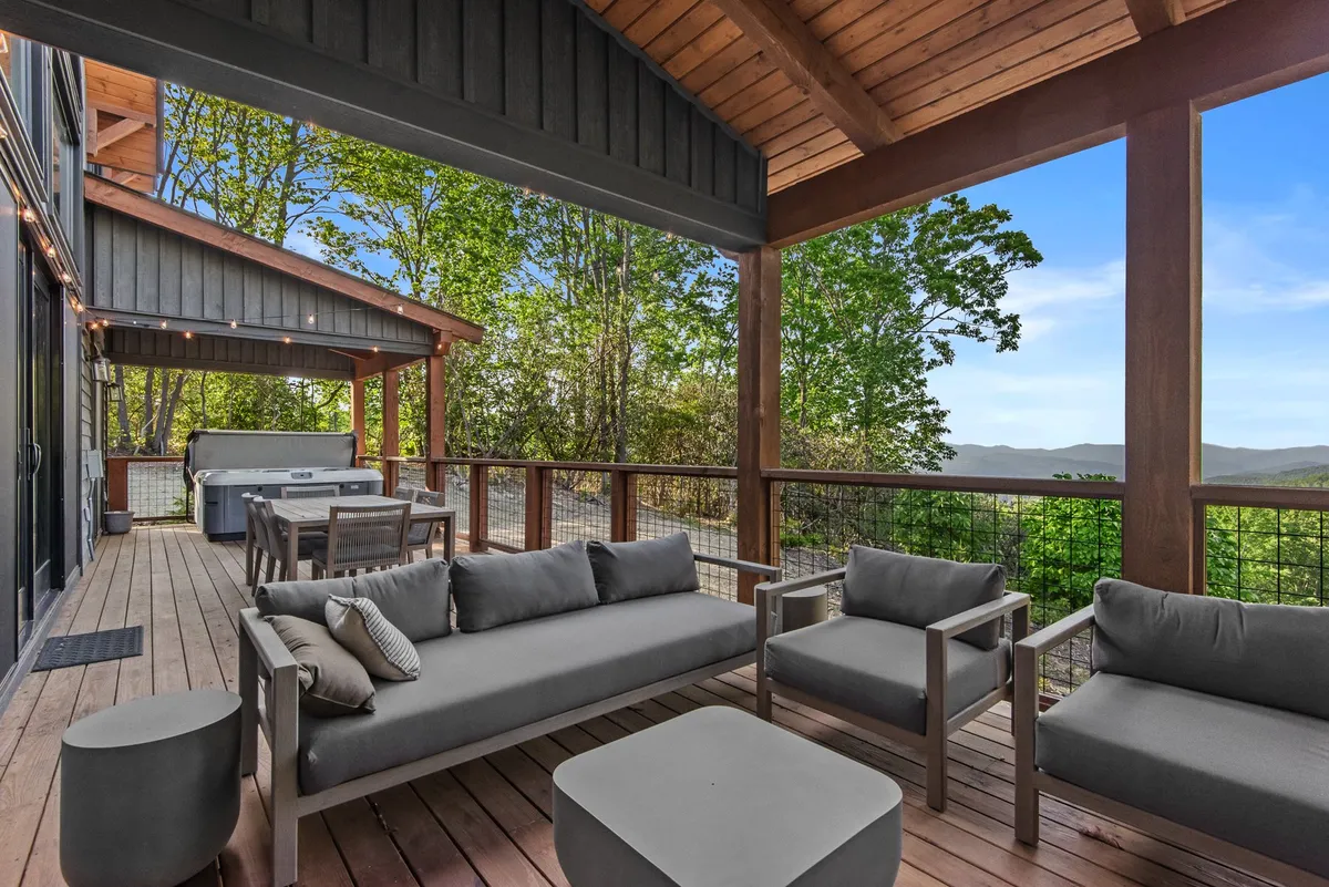 A comfortable seating area on a wooden deck, enveloped by natural scenery. The deck offers sweeping views of the mountains and is set up for relaxation and entertaining, providing a seamless indoor-outdoor experience.