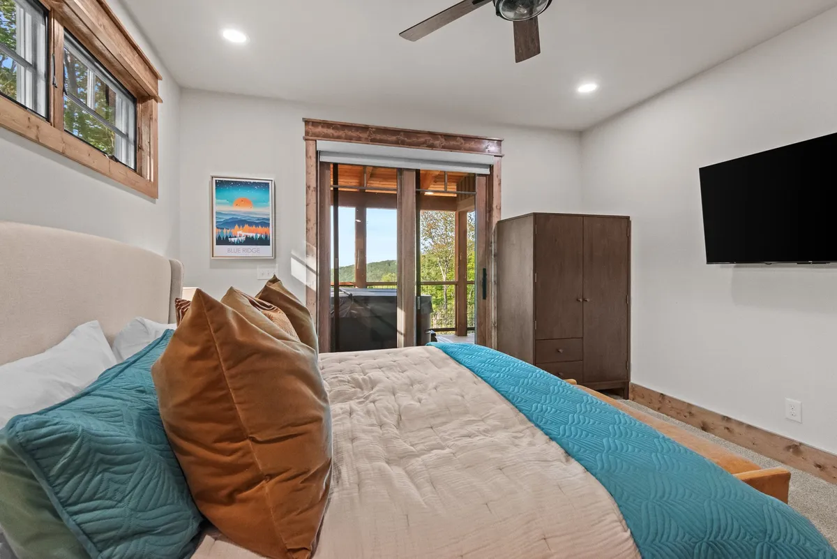 A second bedroom featuring a cozy bed, a window offering a peek at the surrounding nature, a wardrobe, and inviting artwork. The space feels comfortable and ideal for couples or older children.